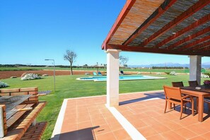 A covered patio with a pool, outdoor furniture, and a view of the landscape.