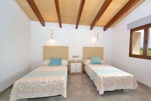 A room with two beds, a nightstand, and a window.