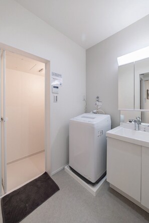 Ein modernes Badezimmer mit Waschmaschine, Waschbecken und Spiegel.