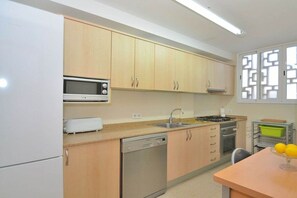 A kitchen with wooden cabinets, a microwave, a dishwasher, a sink, and a stove. - Apartment in Alcudia with terrace (Alcudia)