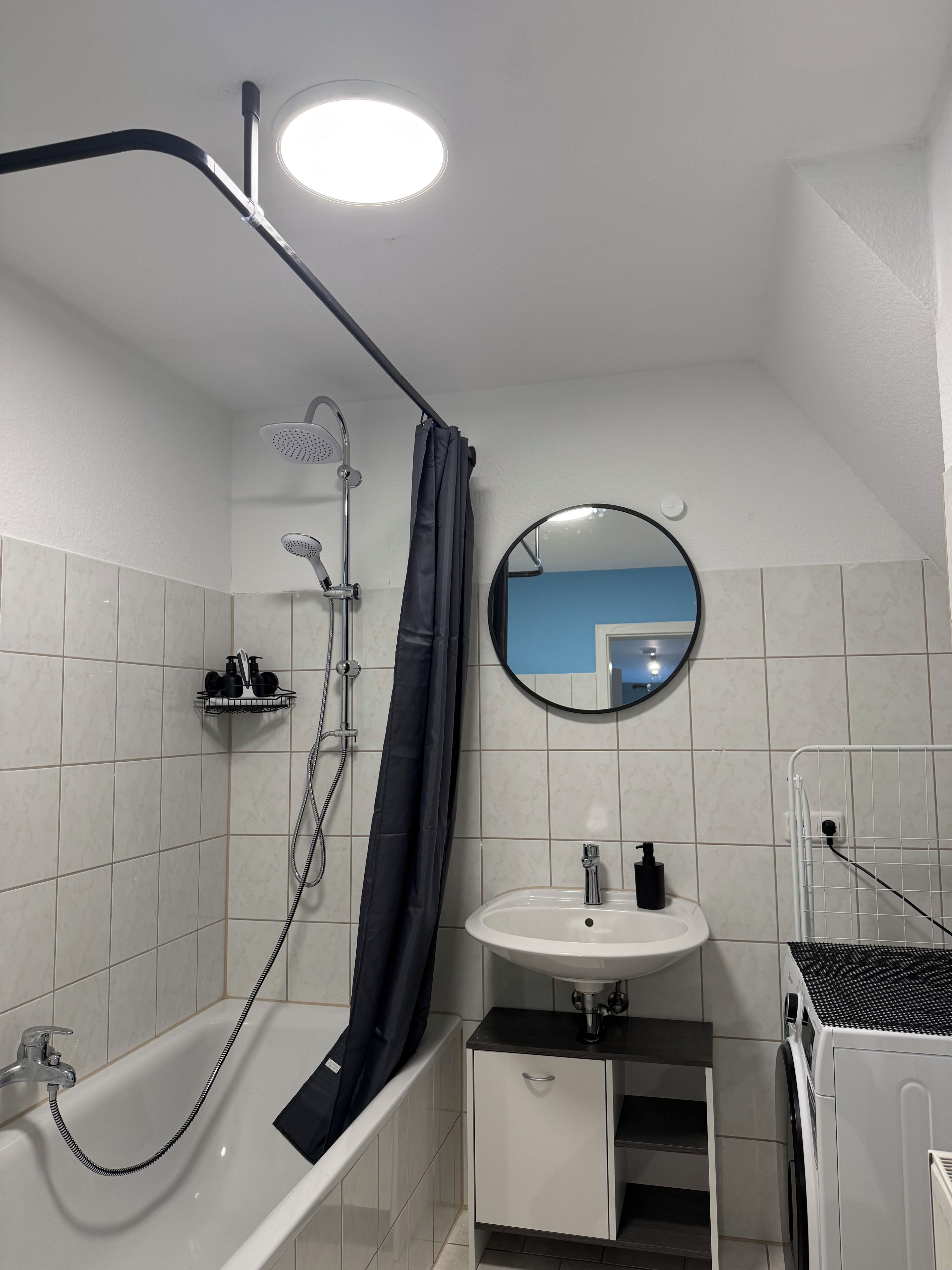 Un baño moderno con bañera, ducha, lavamanos y un espejo.