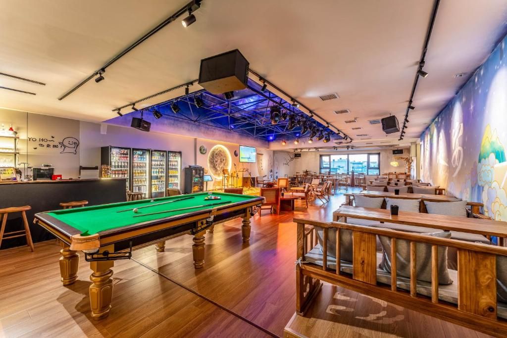 A billiards room with a pool table, seating area, and bar.