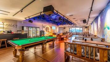 A billiards room with a pool table, seating area, and bar.
