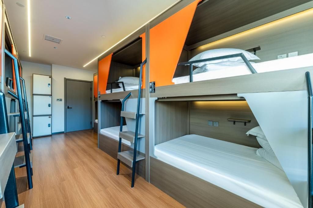 A bunk bed room with a wooden floor, a desk, and a chair.