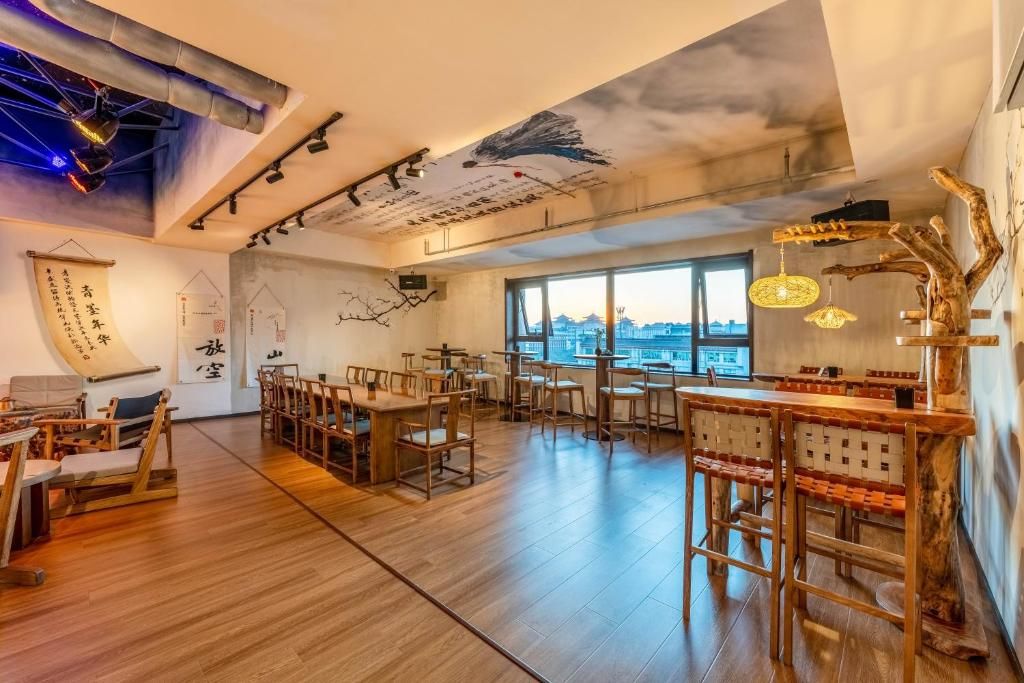 Un vaste espace dédié à la salle à manger, avec des tables et des chaises en bois, un coin bar doté de tabourets, et une vue sur la ville grâce à de grandes fenêtres.