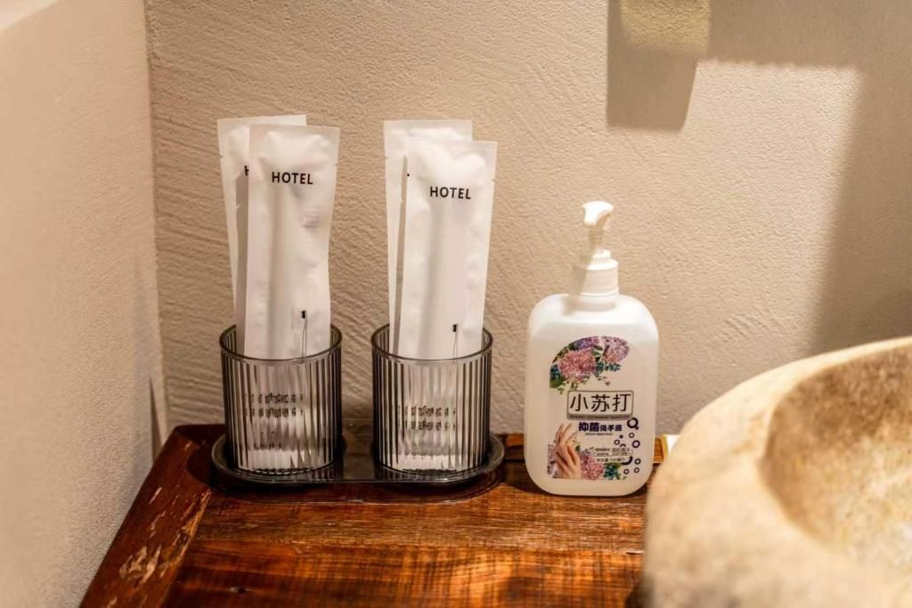 A hotel room with a wooden side table holding a tissue dispenser and a bottle of hand sanitizer.