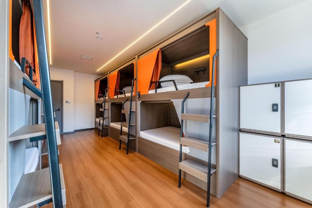 Habitación con literas, suelo de madera, armario y un refrigerador pequeño.