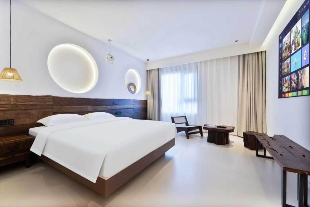 A modern hotel room with a large bed, a desk, and a chair.