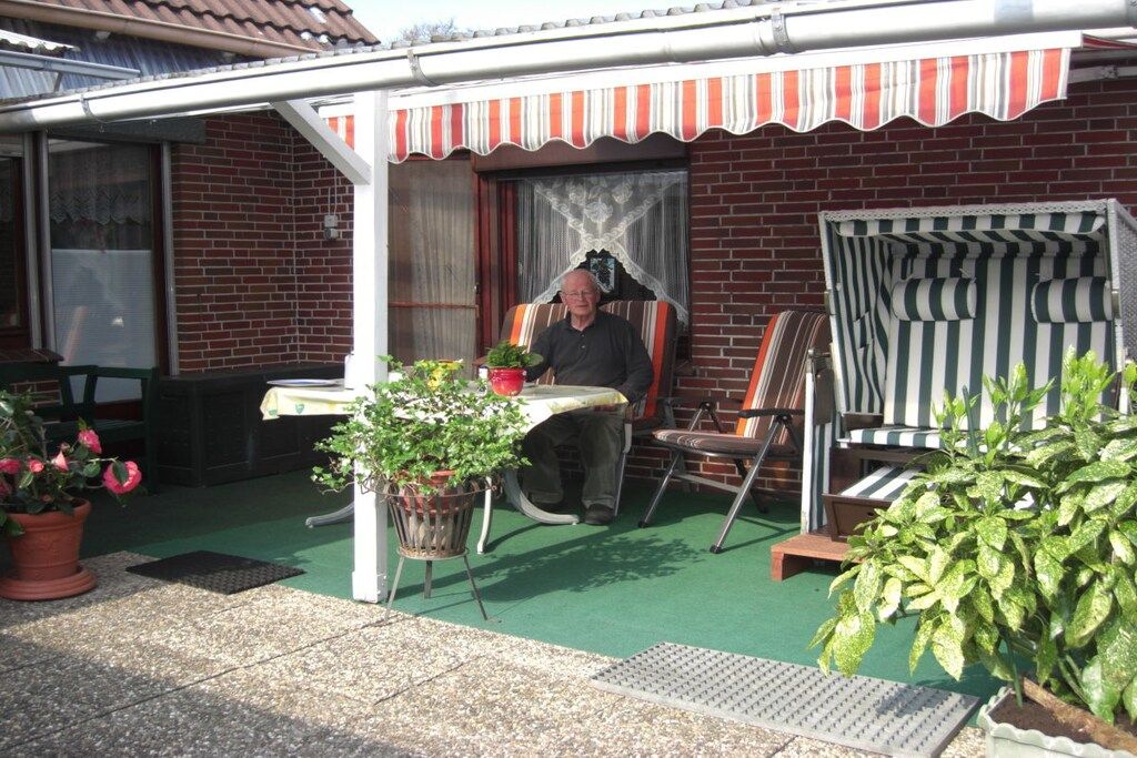 Una zona patio esterna con un muro in mattoni, una zona relax coperta con cuscini a righe e piante in vaso.
