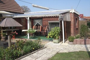 A residential property with a covered porch, outdoor seating, and a garden area. - Holiday apartment with 2 bedrooms (Dornumersiel)