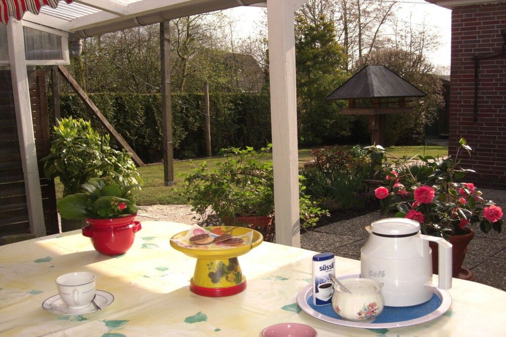 Une table dressée à l’extérieur, avec une cafetière, une tasse et une assiette remplie de nourriture.
