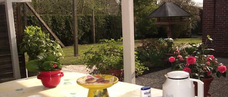 A table set outdoors with a coffee maker, a cup, and a plate with food.