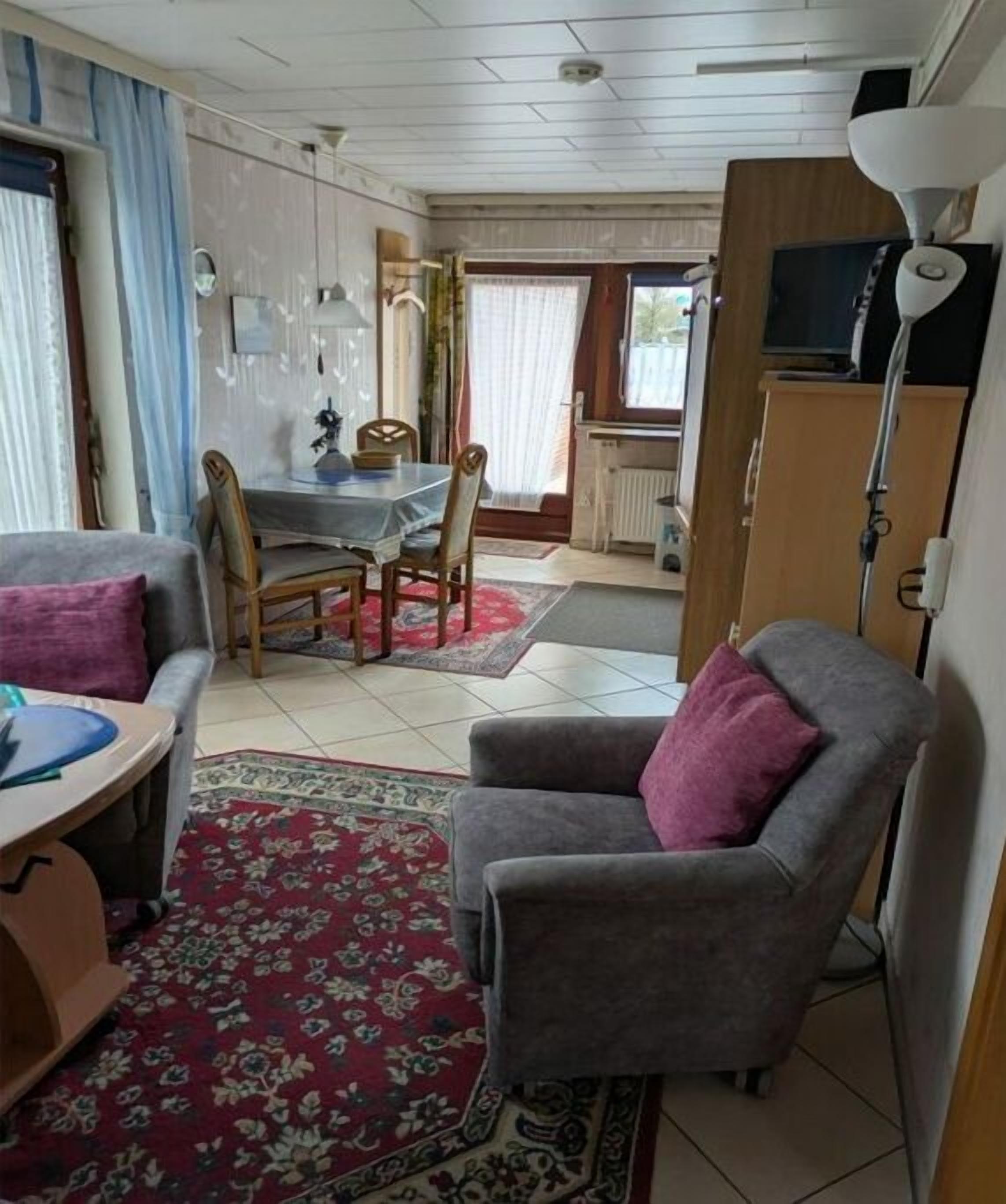 A compact living space with a dining area, a sofa, a television, and a lamp.