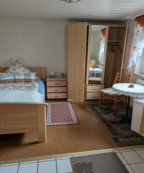 Ein Schlafzimmer mit einem Bett, einem Kleiderschrank, einem Schreibtisch und einem Stuhl.