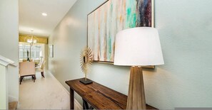 A hallway with a dining area, a lamp, and a painting on the wall. - Go 43 Champions Gate (Davenport)