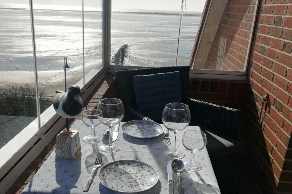 Une table à manger dressée avec des assiettes, des verres et des couverts, donnant sur un paysage enneigé.