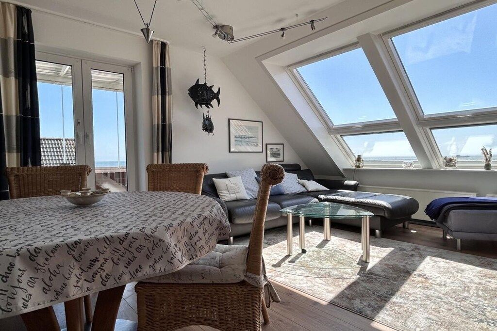 A modern loft-style living space with a dining area, a sofa, and a glass coffee table.