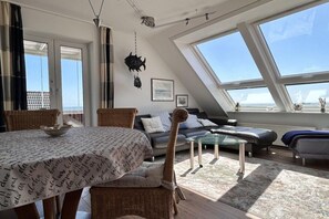 A modern loft-style living space with a dining area, a sofa, and a glass coffee table. - Holiday apartment with 2 bedrooms (Wittdün)