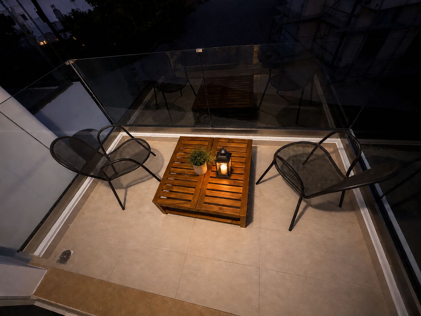 Un balcón con una mesa de madera, dos sillas y una planta en maceta.