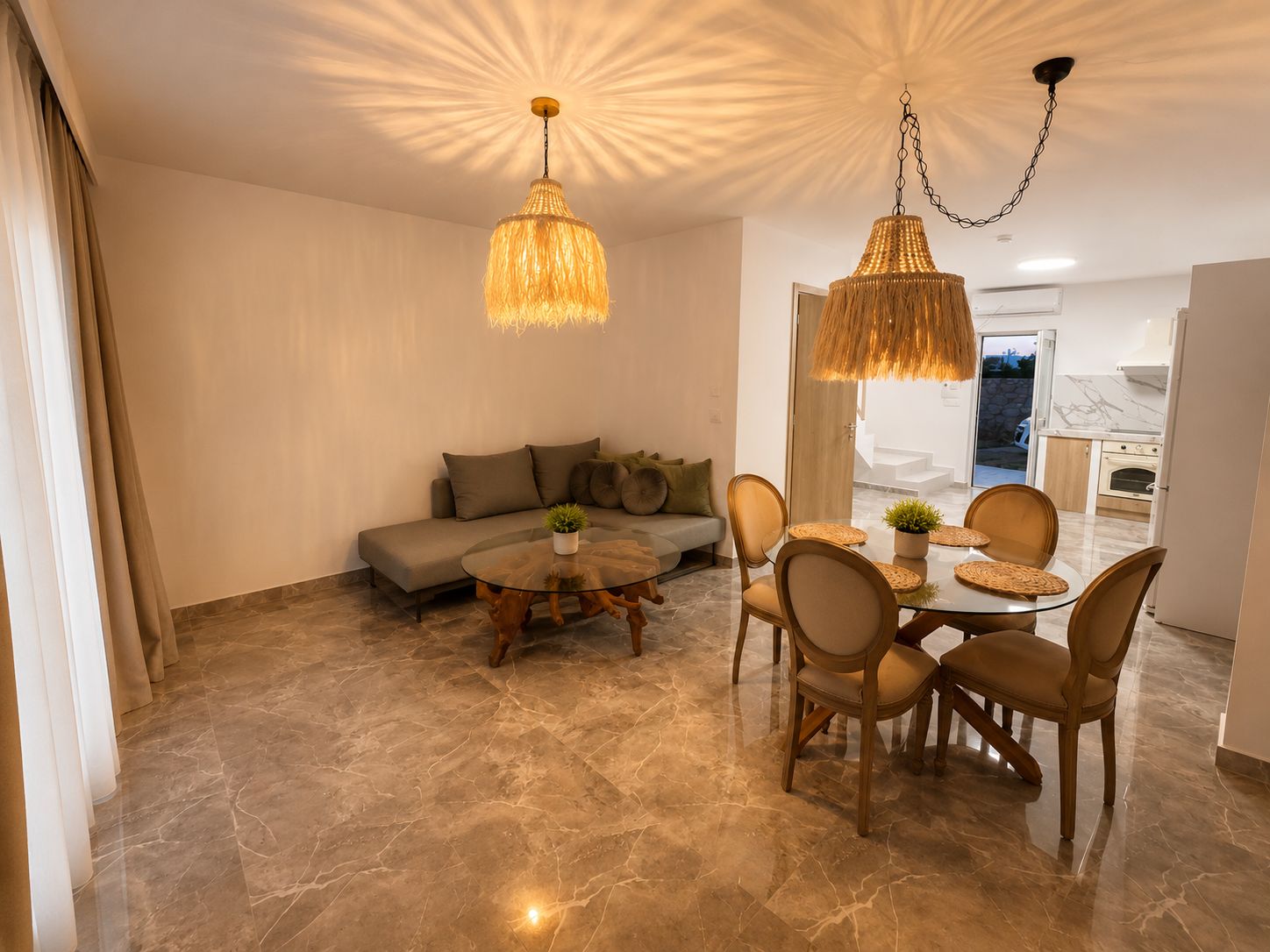A modern living room with a sofa, a round glass coffee table, and a dining area with a table and chairs.