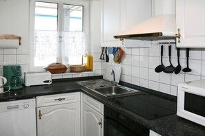 A kitchen with white cabinets, a black countertop, a stainless steel sink, and a microwave. - ||-----------------------at the Amber Spa---------------|| (Zinnowitz)