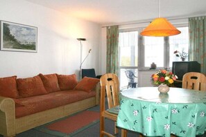 A cozy living room with a sofa, chairs, a dining table with a floral tablecloth, and a vase of flowers. - ||-----------------------at the Amber Spa---------------|| (Zinnowitz)