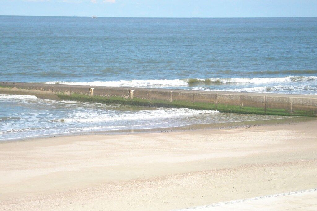 A beach with a concrete barrier separating the sand from the ocean.