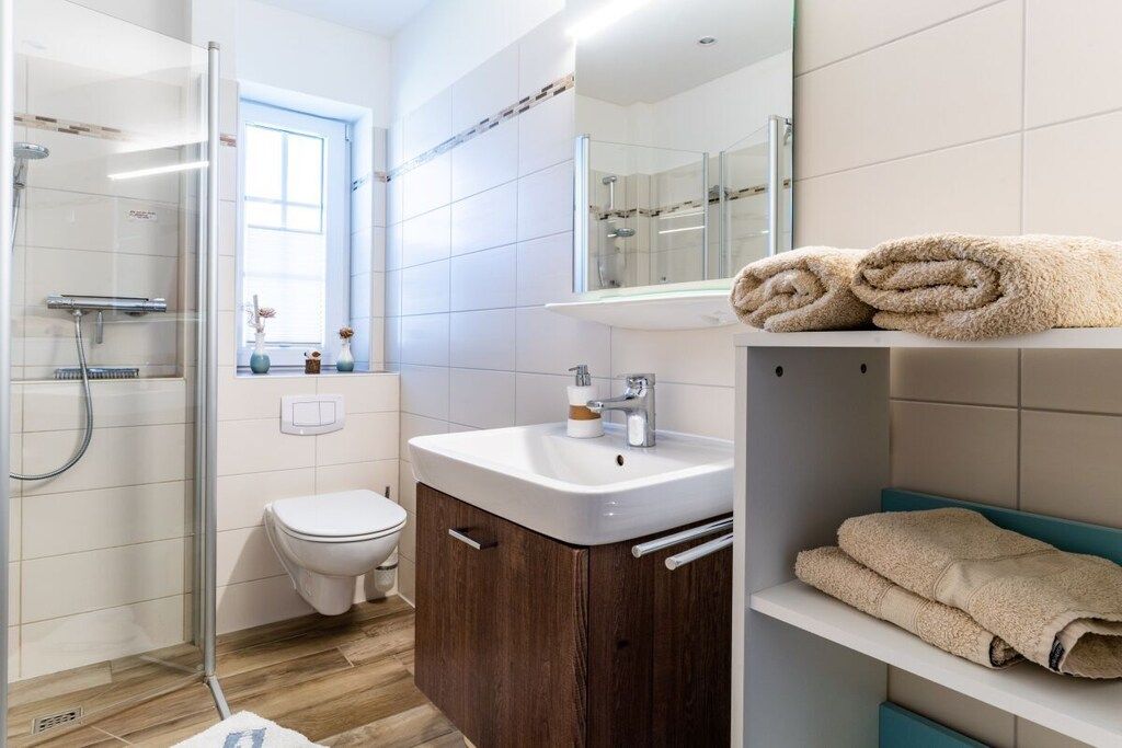Une salle de bain moderne avec une douche à parois de verre, un lavabo blanc et des toilettes.