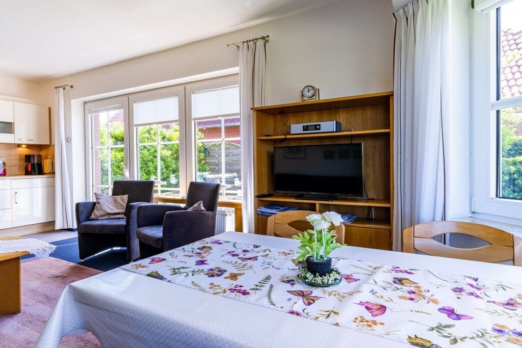 Ein Zimmer mit einem Bett, einem Fernseher, einem Esstisch und Blick auf Grünflächen.