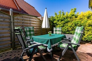 An outdoor patio with a table and chairs, a white umbrella, and a wooden fence. - Holiday apartment with 1 bedroom (Borkum)