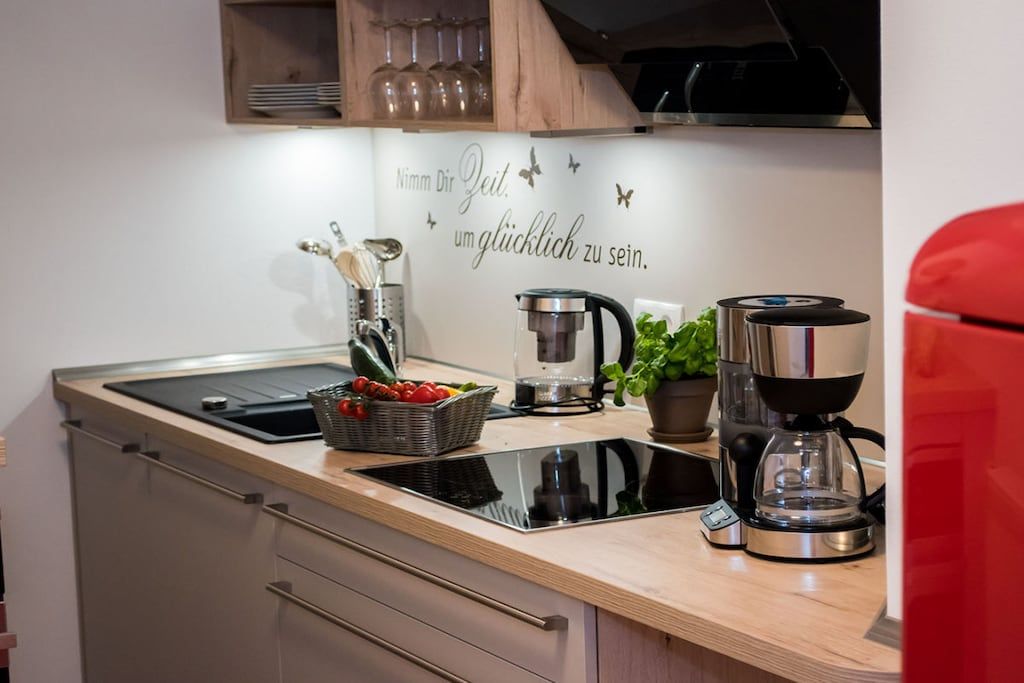 Une cuisine moderne équipée d’une cuisinière intégrée, d’une machine à café et d’un panier de fruits posé sur le plan de travail.