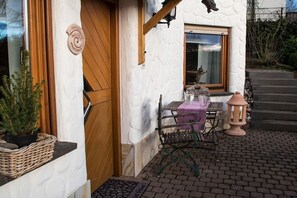 A rustic outdoor seating area with a table and chairs, a lantern, and a small statue. - Holiday apartment with 1 bedroom (0chtendung)