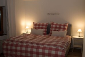 A neatly made bed with a checkered bedspread, two bedside lamps, and a wall sign. - Holiday apartment with 1 bedroom (0chtendung)