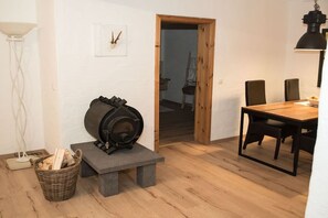 A room with a stone bench, a table with chairs, a floor lamp, and a fireplace. - Holiday apartment with 1 bedroom (0chtendung)