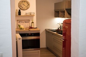 A compact kitchen with a clock, a sign, and a red refrigerator. - Holiday apartment with 1 bedroom (0chtendung)