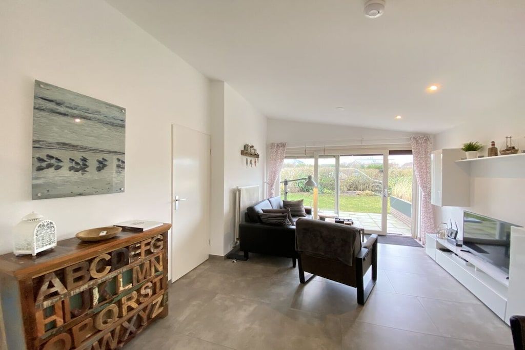 Un salon moderne avec une cheminée, une table basse et un canapé. Une grande fenêtre, ornée de rideaux, offre une vue sur l’extérieur.