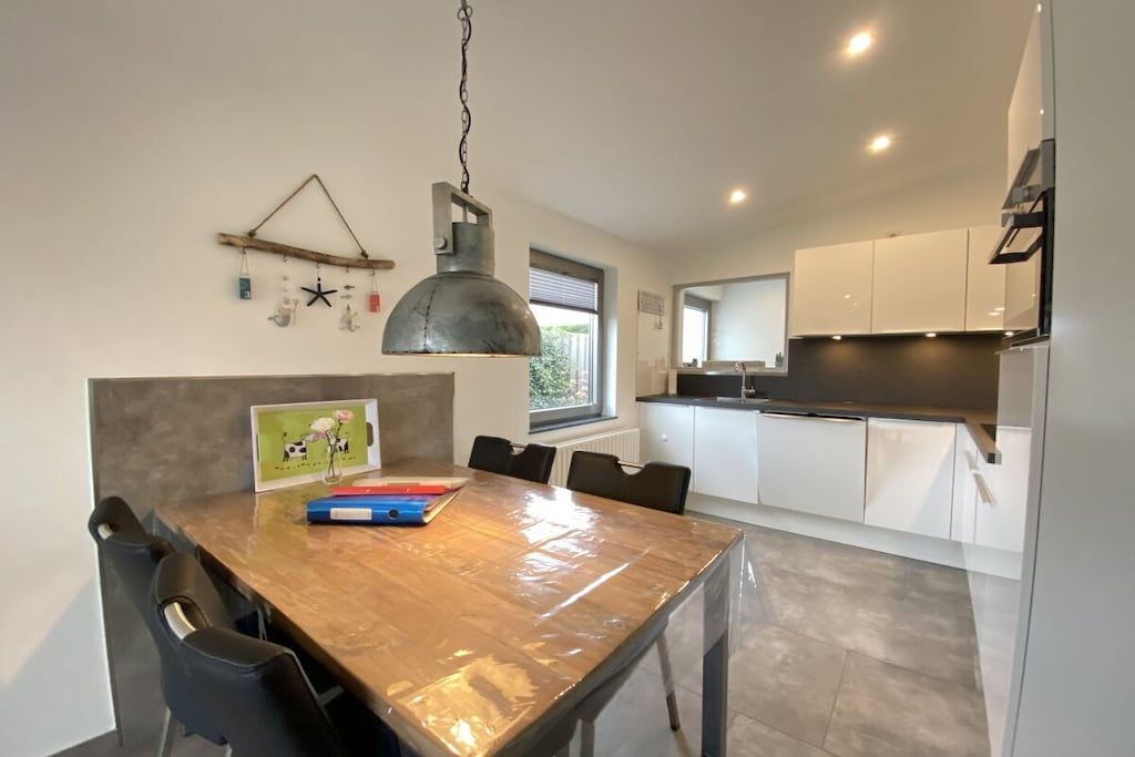 Une cuisine moderne avec des meubles blancs et une table à manger en bois.