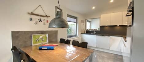A modern kitchen with white cabinets and a wooden dining table.