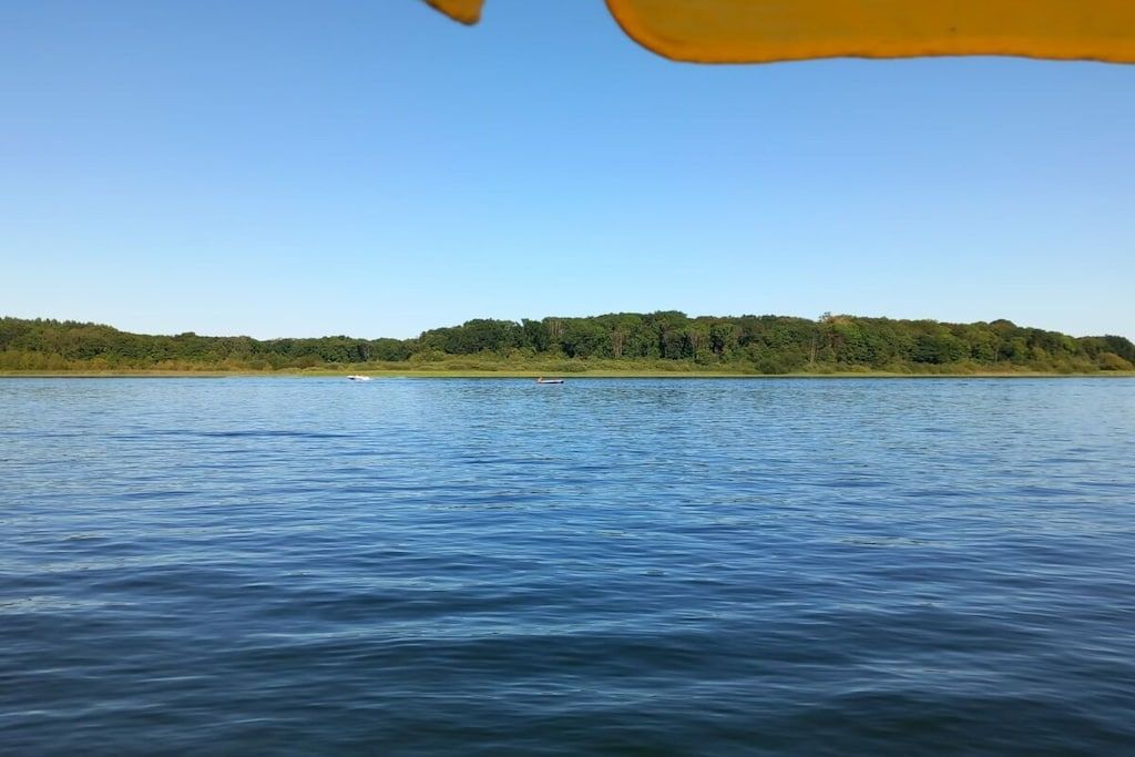 Een kalm meer met een boot en een bebost oever.