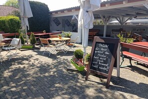 An outdoor seating area with tables and chairs, a chalkboard sign, and potted plants. - Holiday apartment with 1 bedroom (Nossentiner Hütte)