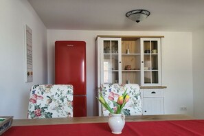 A room with a red refrigerator, a white cabinet with glass doors, and a floral-patterned chair. - Holiday apartment with 1 bedroom (Nossentiner Hütte)