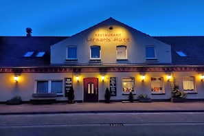 A building with a sign reading 'RESTAURANT Urban's Hütte' and multiple windows with lights on. - Holiday apartment with 1 bedroom (Nossentiner Hütte)