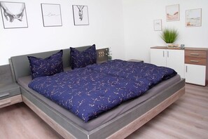 Ein Schlafzimmer mit einem Bett, einem Nachttisch, einer Kommode und Wandbildern.