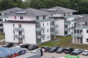 Edifício residencial com várias varandas, área de estacionamento e painel solar no telhado.