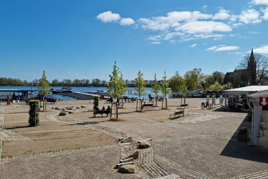 An outdoor area with a paved walkway, benches, and a small kiosk.