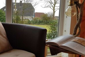 A room with a large window, a chair, and a book on a table. - Holiday apartment with 1 bedroom (Kappeln-Kopperby)