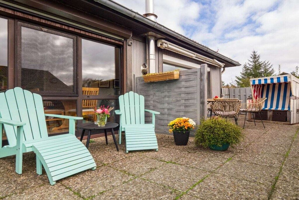 Un espace patio aménagé avec des sièges d’extérieur, comprenant deux chaises et une table, ainsi qu’une petite plante en pot.