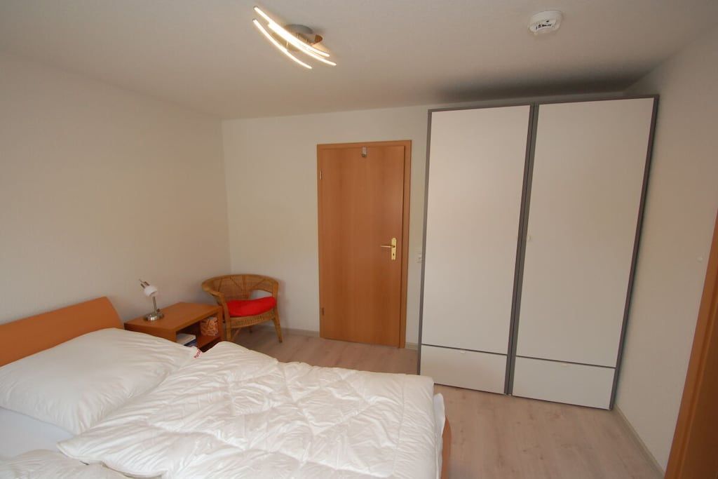 Ein Schlafzimmer mit Bett, Stuhl, Kleiderschrank und einer Tür.