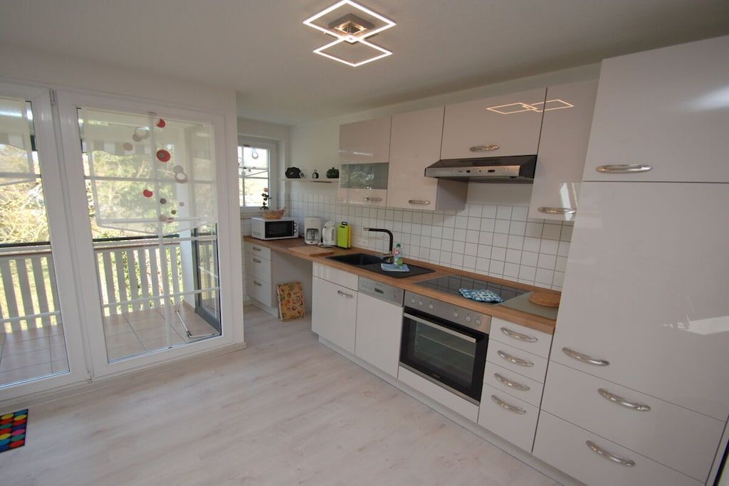 A modern kitchen with white cabinets, a microwave, and a sink.