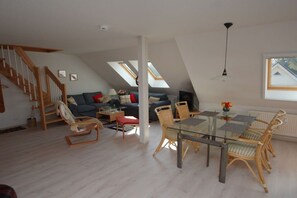 A spacious loft with a dining area, a staircase, and a living room with a sofa and chairs. - Holiday apartment with 1 bedroom (Ostseebad Prerow)